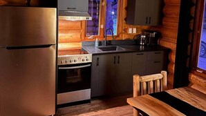 A compact kitchen with a stainless steel refrigerator, a built-in oven, a stove, and wooden cabinetry. - 108 Rte du Valinouet (Saint-David-de-Falardeau)