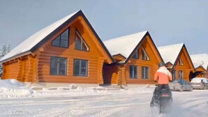 Une rangée de cabanes en rondins, le sol étant recouvert de neige.