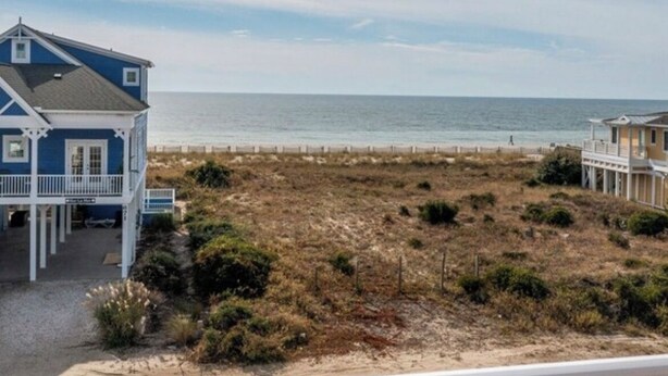 Een huis aan de kust met een balkon dat uitkijkt over het strand.