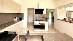A modern kitchen with a built-in stove, oven, and sink, and a dining area with a large mirror and a TV.