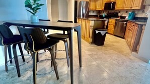 Een moderne keuken met houten kastjes, roestvrijstalen apparatuur en een eethoek met een tafel en stoelen.