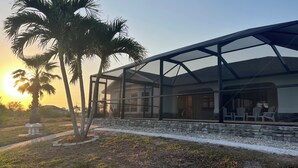 Een modern huis met een overdekte patio, stenen muren en palmbomen.