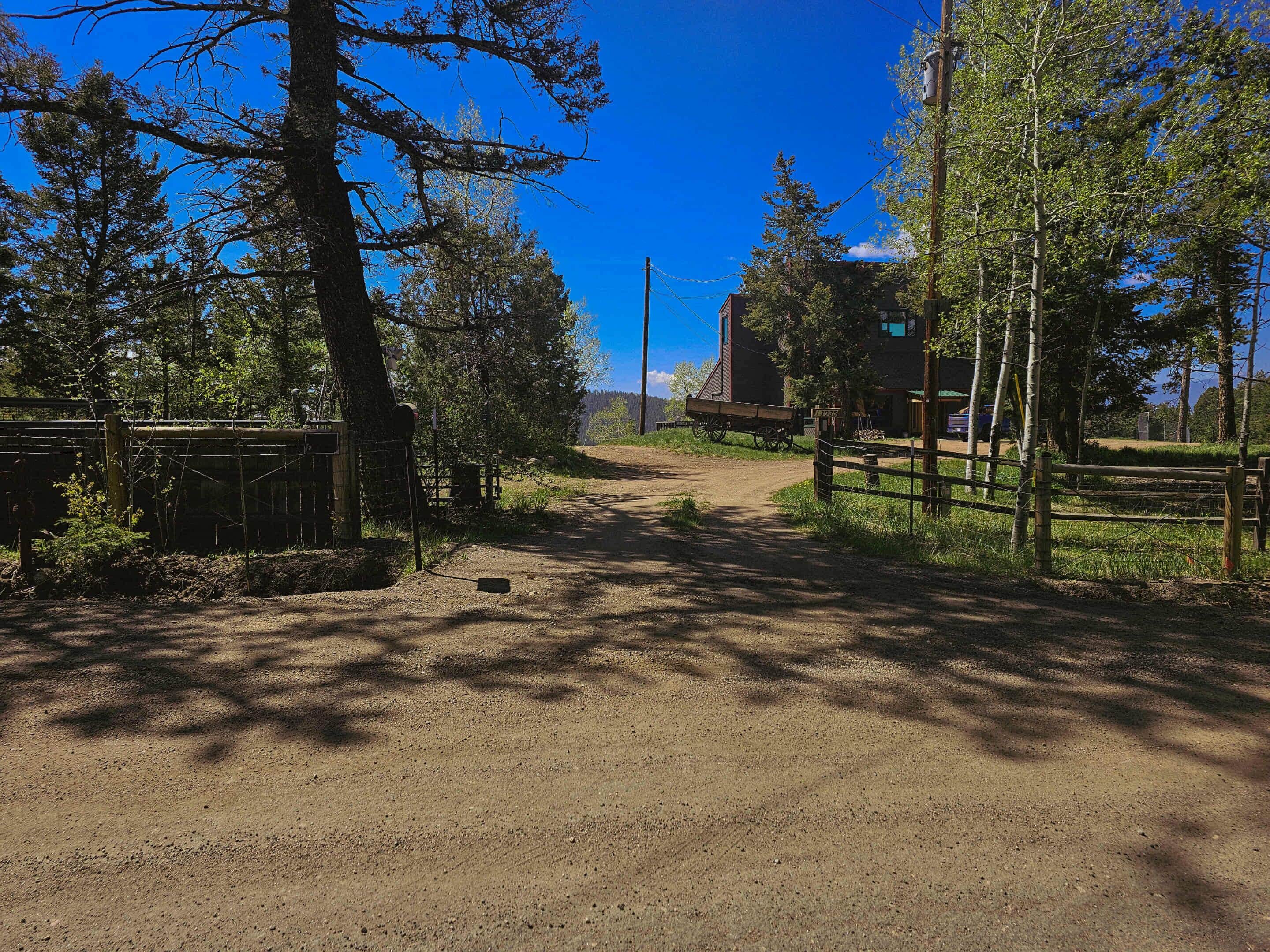 A dirt path leading to a rustic building surrounded by trees.