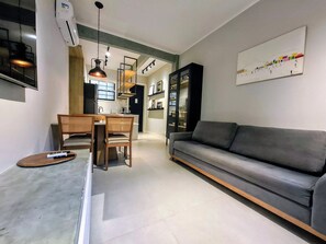 A modern living room with a grey sofa, wooden dining table, and pendant lighting. - Leblon- Design e aconchego.  (Rio de Janeiro)