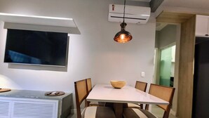 Un coin repas avec une table blanche, des chaises en bois, un bol et une suspension.