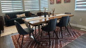 A modern living room with a dark sofa, a wooden dining table, and a patterned rug. - Family Retreat, Fire Pit • EV Charger • Near Denver • Sleeps 9 (Arvada)