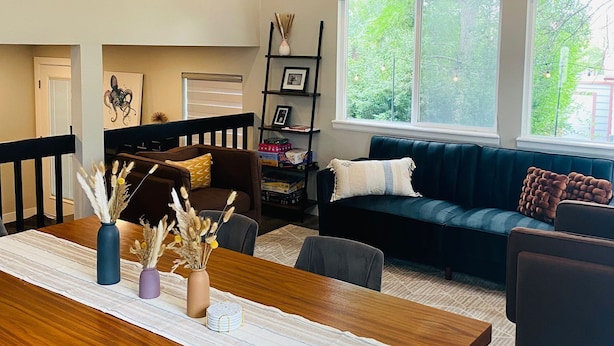 A spacious living room with a wooden dining table, a dark blue sofa, and a ceiling fan. - Family Retreat, Fire Pit • EV Charger • Near Denver • Sleeps 9 (Arvada)