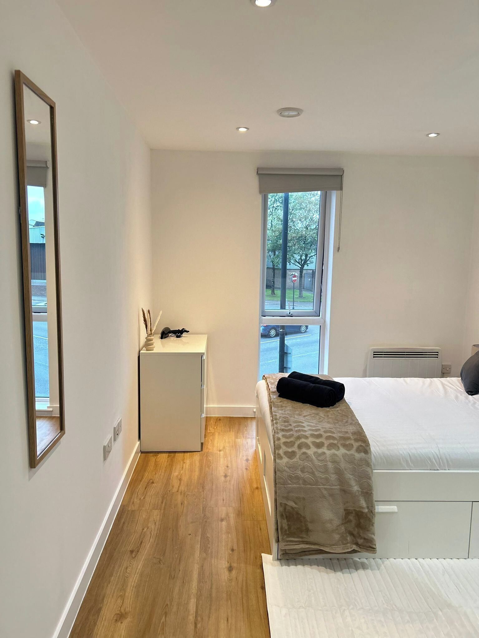 Un dormitorio moderno con una cama, un escritorio pequeño y una ventana que ofrece vistas al exterior.