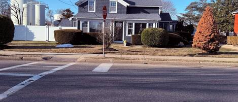 A residential house with a front yard, a stop sign, and a crosswalk.