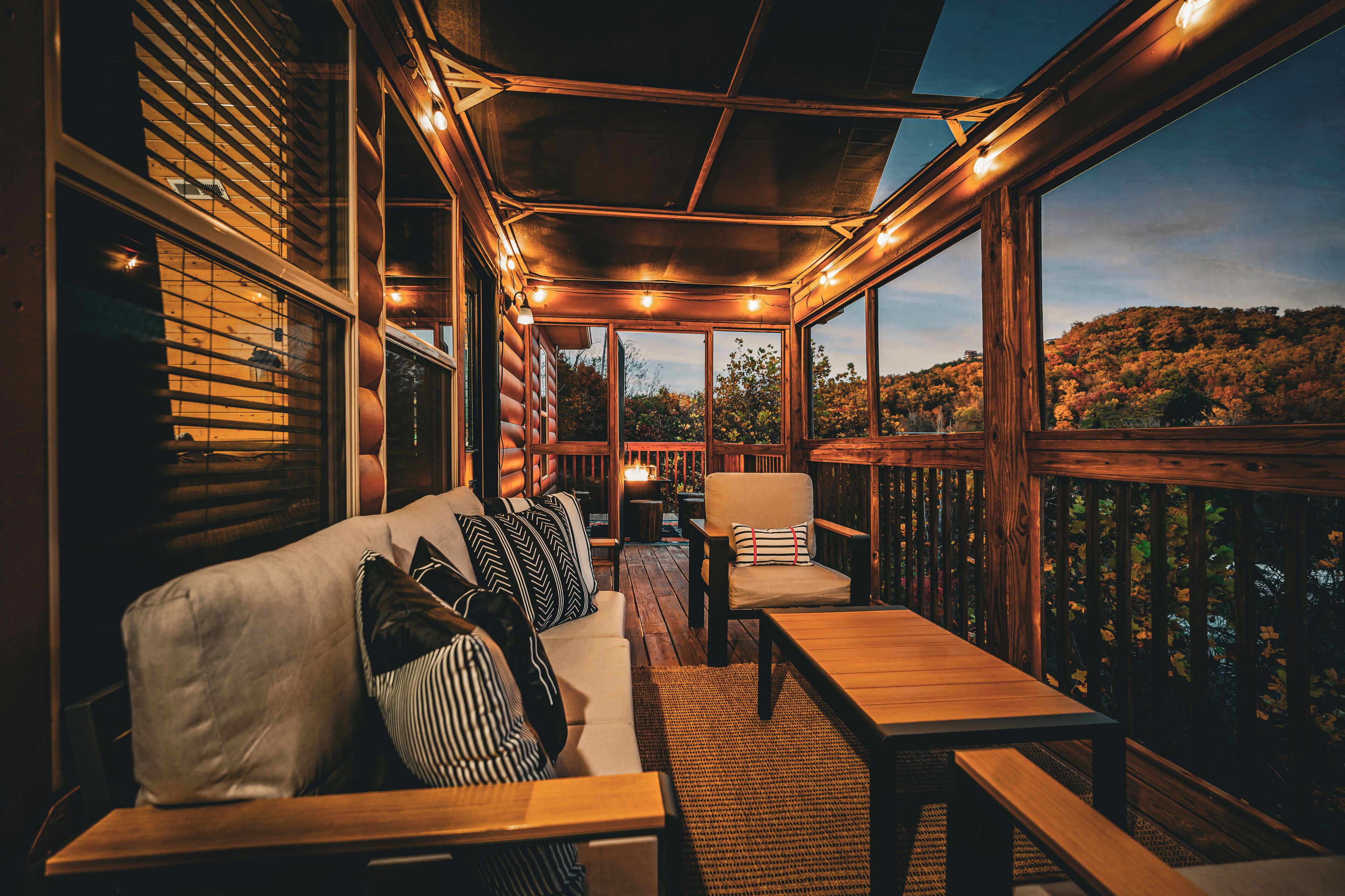 An outdoor deck with a wooden bench, a sofa with striped cushions, and a chair.