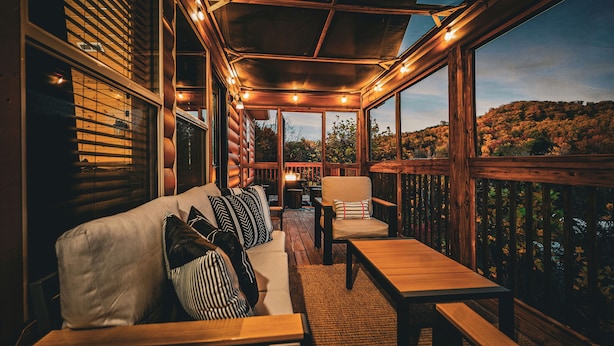 Una terrazza all'aperto con una panca di legno, un divano con cuscini a righe e una sedia.