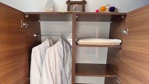En garderob i trä med flera hyllor, en klädstång och en liten hylla med dekorativa föremål.