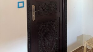 En mörk träport med detaljerade sniderier och ett modernt handtag.