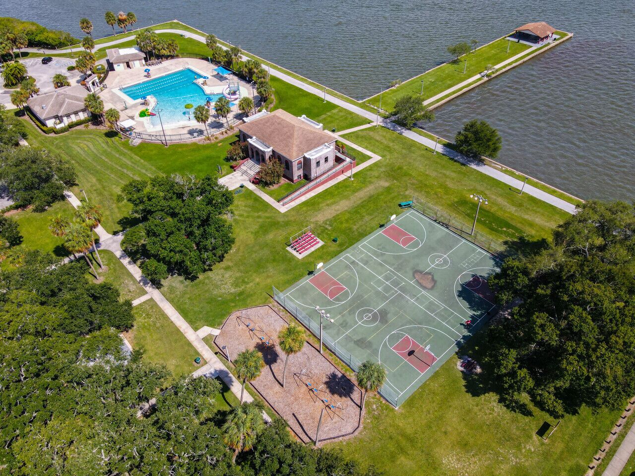 An aerial view of a residential property with a swimming pool, tennis courts, and a house.