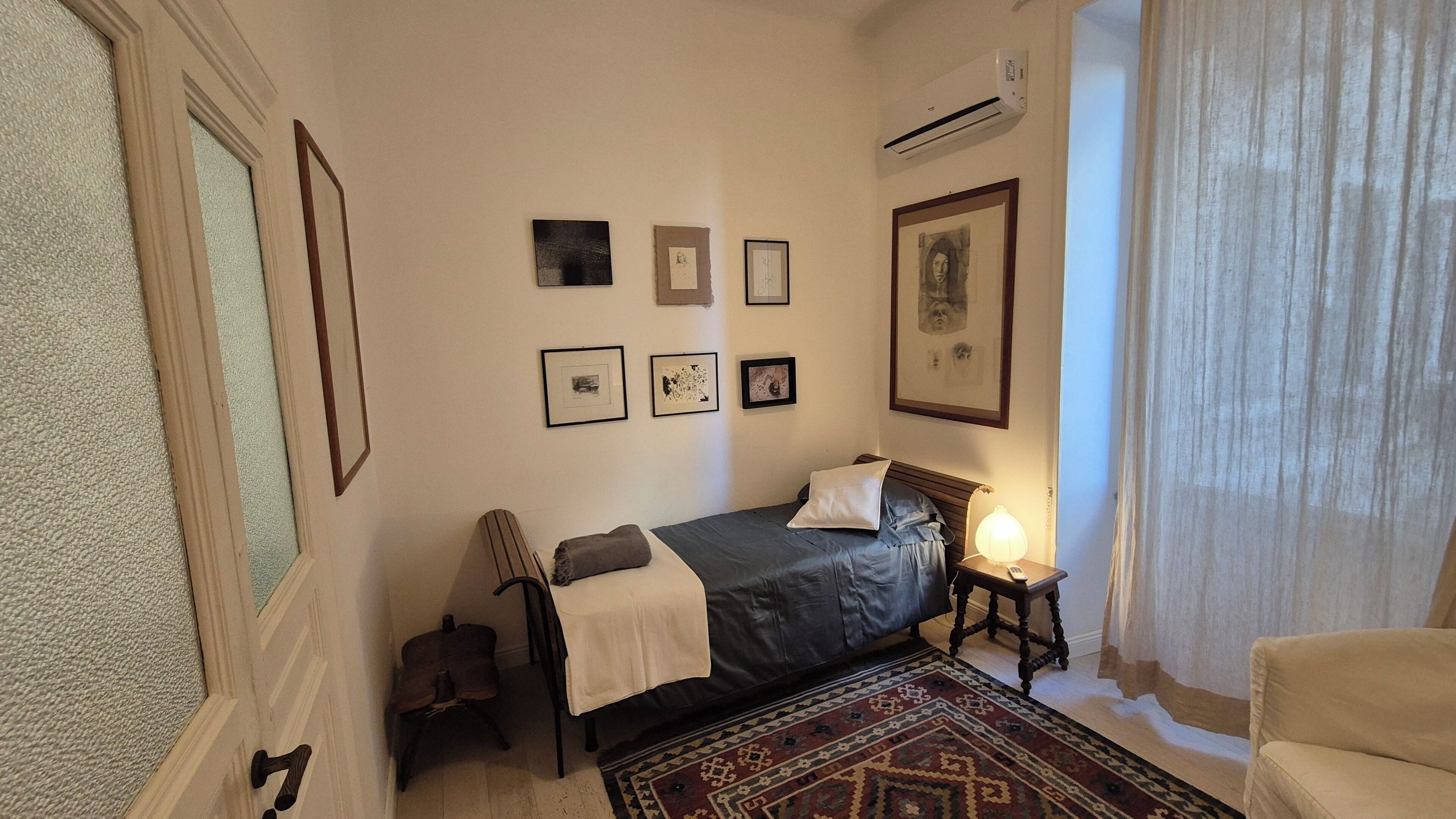 A bedroom with a bed, a chair, a nightstand, and a rug.
