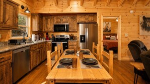 A wooden cabin interior with a kitchen, dining area, and a bed. - Romantic Log Cabin • Hot Tub + Vinyl Records • 15 Min to Ellijay (Ellijay)