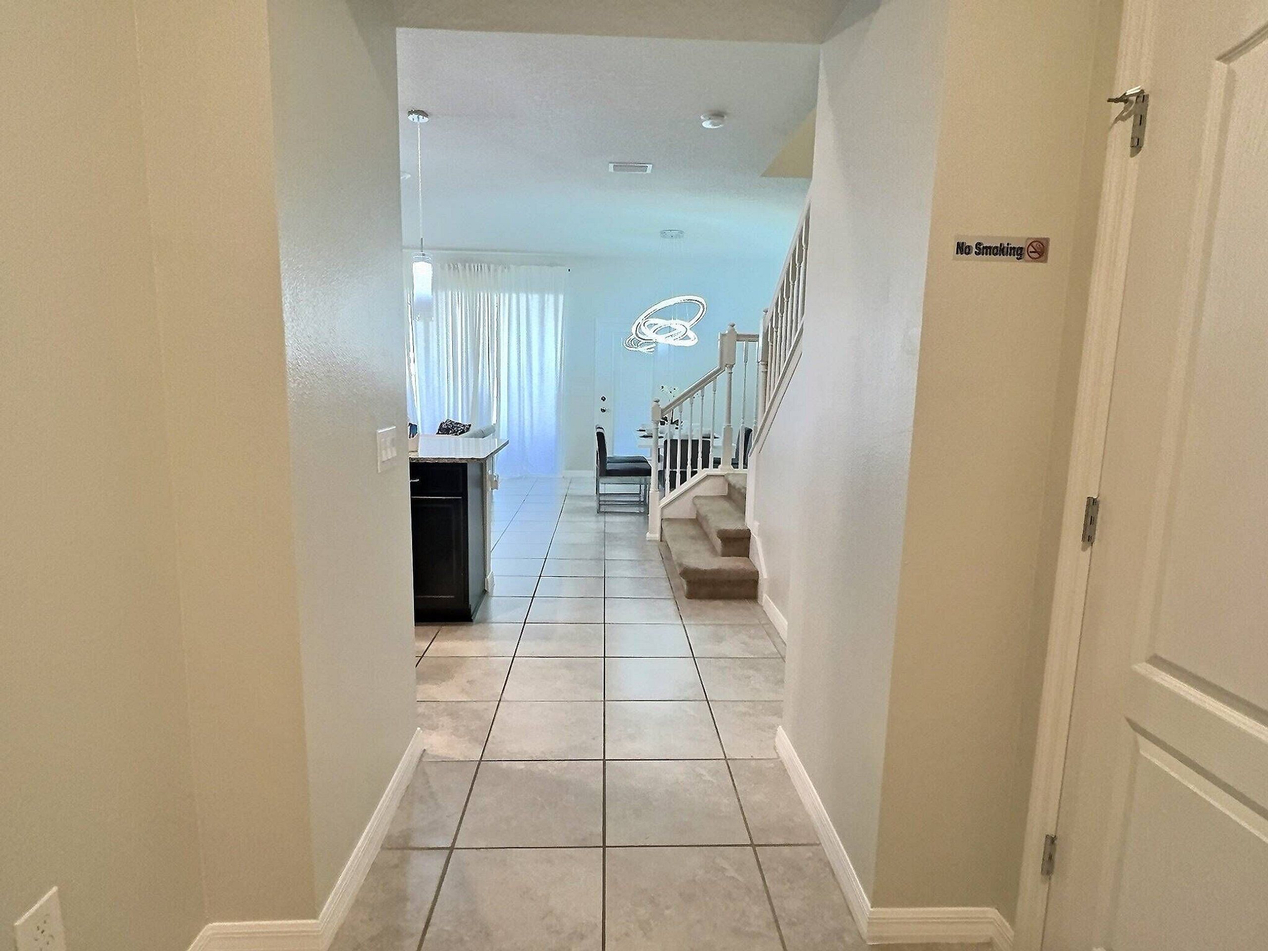 A hallway with a kitchen area, a staircase, and a 'No Smoking' sign.