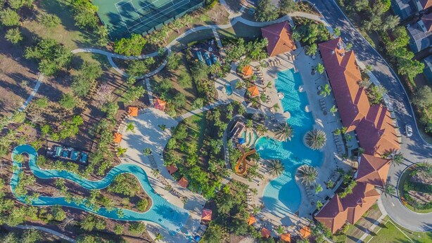 An aerial view of a resort with multiple swimming pools, a water slide, and a variety of outdoor seating areas surrounded by palm trees and greenery. - Solterra 5BR Villa - Private Pool & Resort (Davenport)
