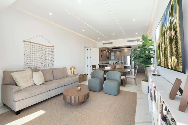 Een moderne woonkamer met een bank, poefs, een salontafel en een boekenkast.
