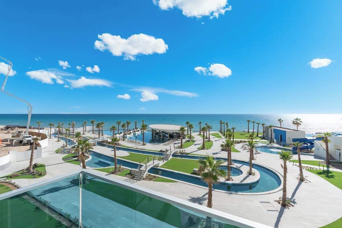 Un resort con area piscina, palme e vista sull'oceano.