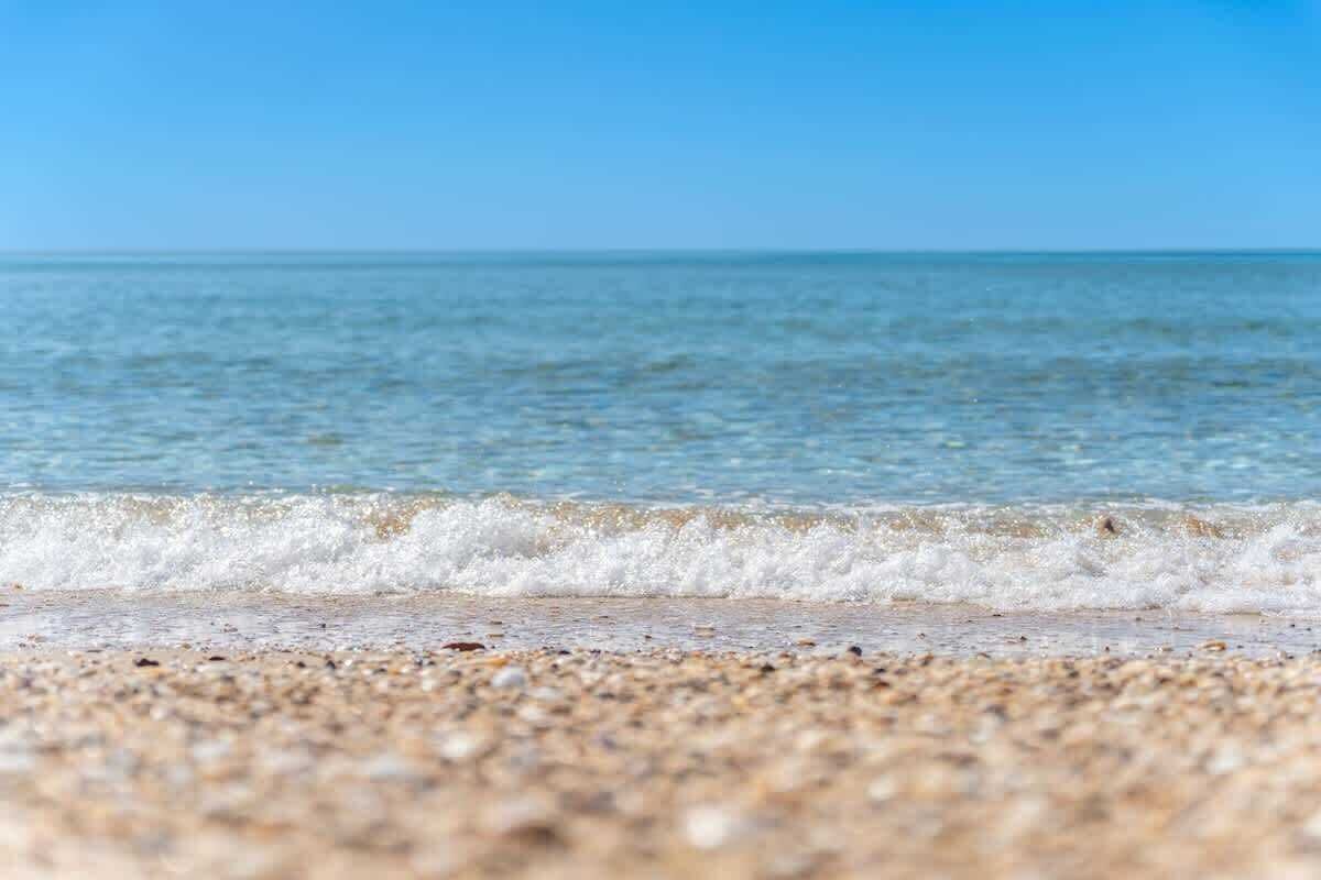 Une plage offrant une vue dégagée sur l’océan et dont le rivage est composé de galets.