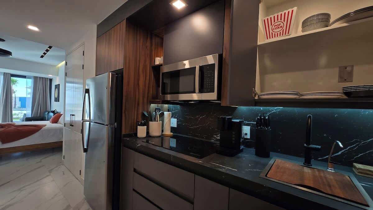 A modern kitchen with a built-in microwave, a coffee machine, and a sink.