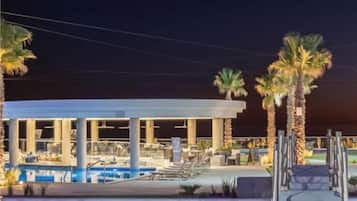 Ett semesterområde med en pool, palmer och ett överbyggt område.
