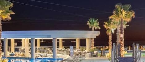 A resort with a pool, palm trees, and a covered area.