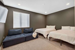 A bedroom with a sofa, two beds, and a window with blinds. - The One | Glendale | Pool & Spa | State Farm (Glendale)