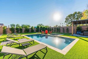 A swimming pool with lounge chairs and a covered seating area. - The One | Glendale | Pool & Spa | State Farm (Glendale)