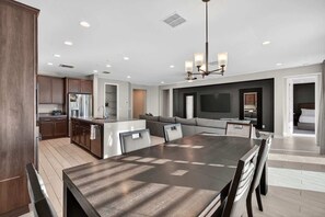 A modern kitchen with a dining area, built-in appliances, and a large island. - The One | Glendale | Pool & Spa | State Farm (Glendale)