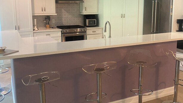 Una cucina moderna con isola centrale, elettrodomestici in acciaio inossidabile e sgabelli da bar.