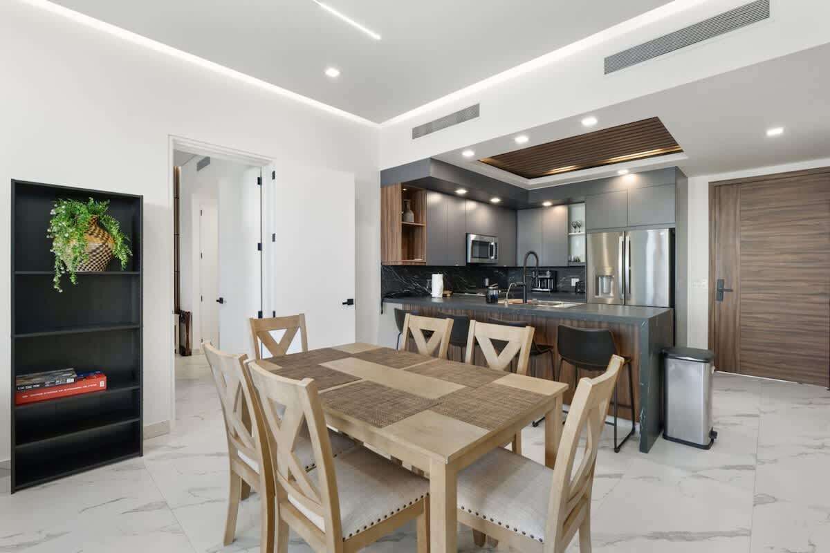 Una cucina moderna con zona pranzo, caratterizzata da un'isola centrale, elettrodomestici integrati e una libreria con oggetti decorativi.