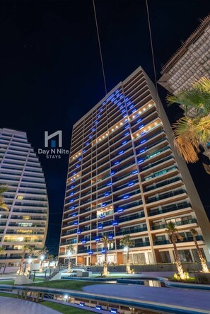 Un hotel de gran altura con varios pisos, balcones y una fachada bien iluminada.