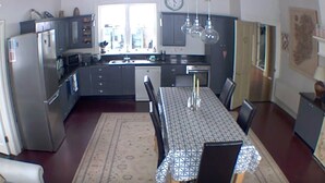 A modern kitchen with a dining table, chairs, and a rug.