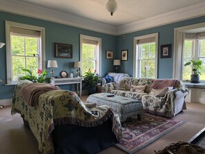 A room with a large window, a sofa set, a small table, and a lamp.