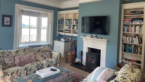 A living room with a sofa, a fireplace, a bookshelf, and a television.
