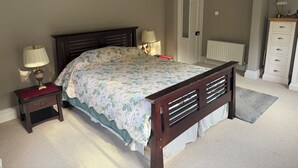 A bedroom with a bed, nightstands, a dresser, a door, and a radiator.