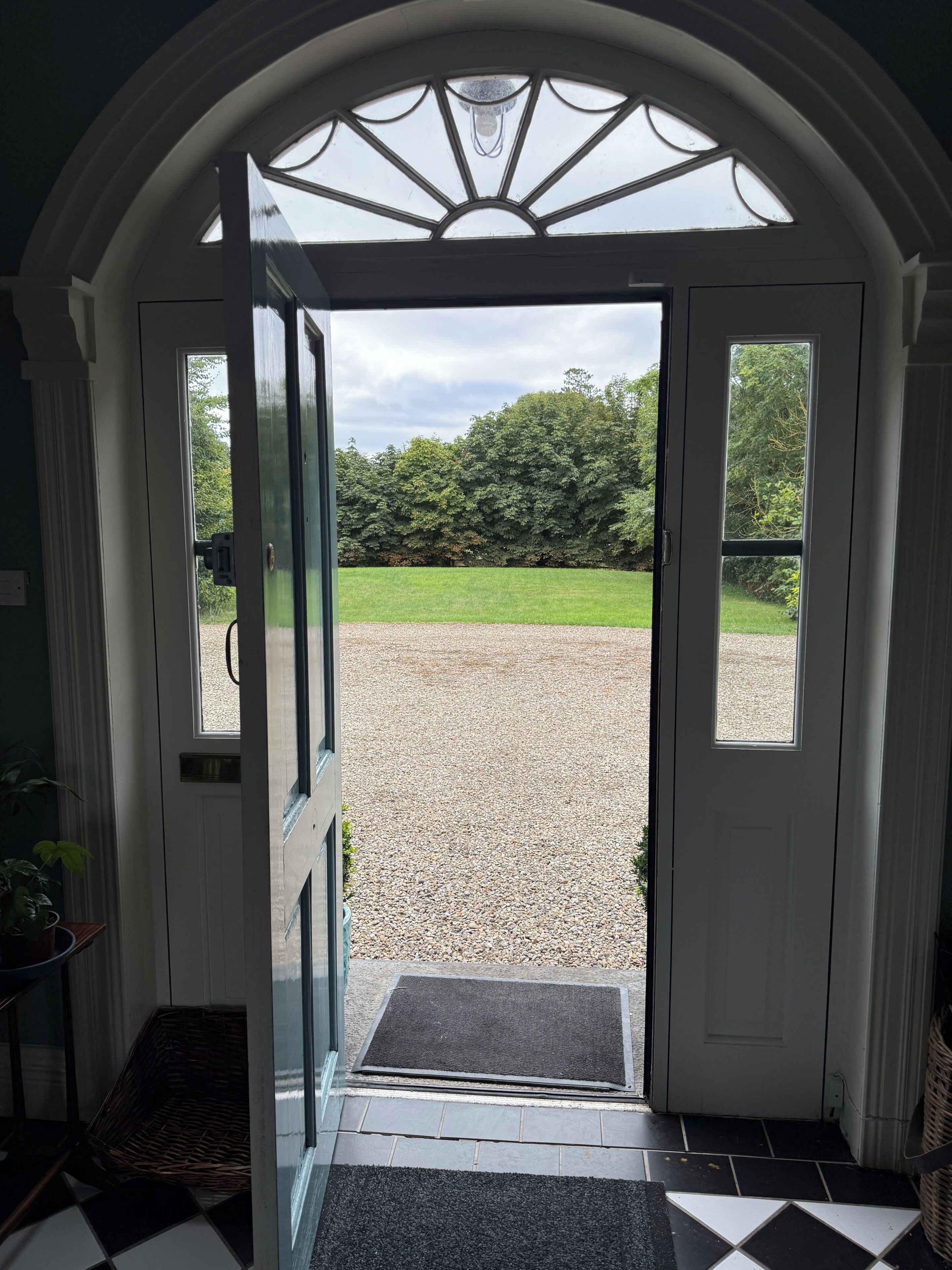 A doorway leading to a gravel area with a view of trees and a lawn.