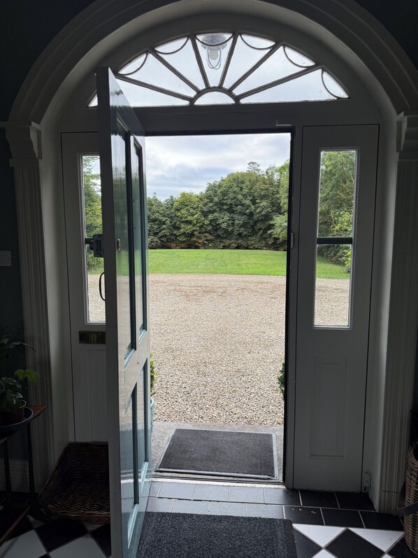 A doorway leading to a gravel area with a view of trees and a lawn.