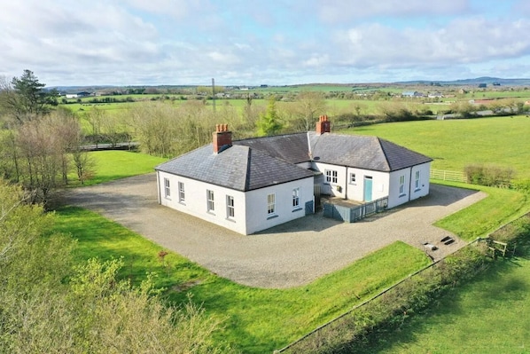 A two-story white house with a gravel driveway and a fenced yard.