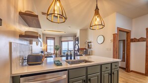 A modern kitchen with a large island, stainless steel appliances, and pendant lighting. - Mountain Soul Retreat (Snowshoe)