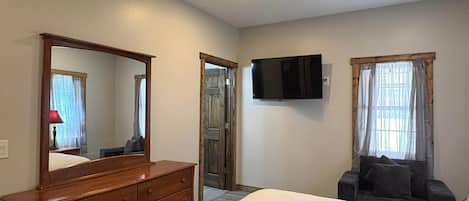Un dormitorio con cama, cómoda, televisor y ventilador de techo.
