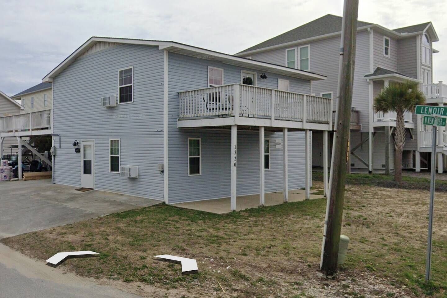 A two-story house with a balcony, a garage, and a visible address sign.