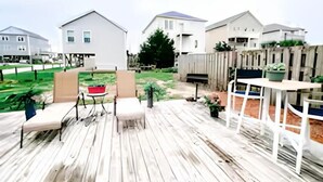 Une terrasse en bois avec des meubles d’extérieur, une petite table et une plante en pot.