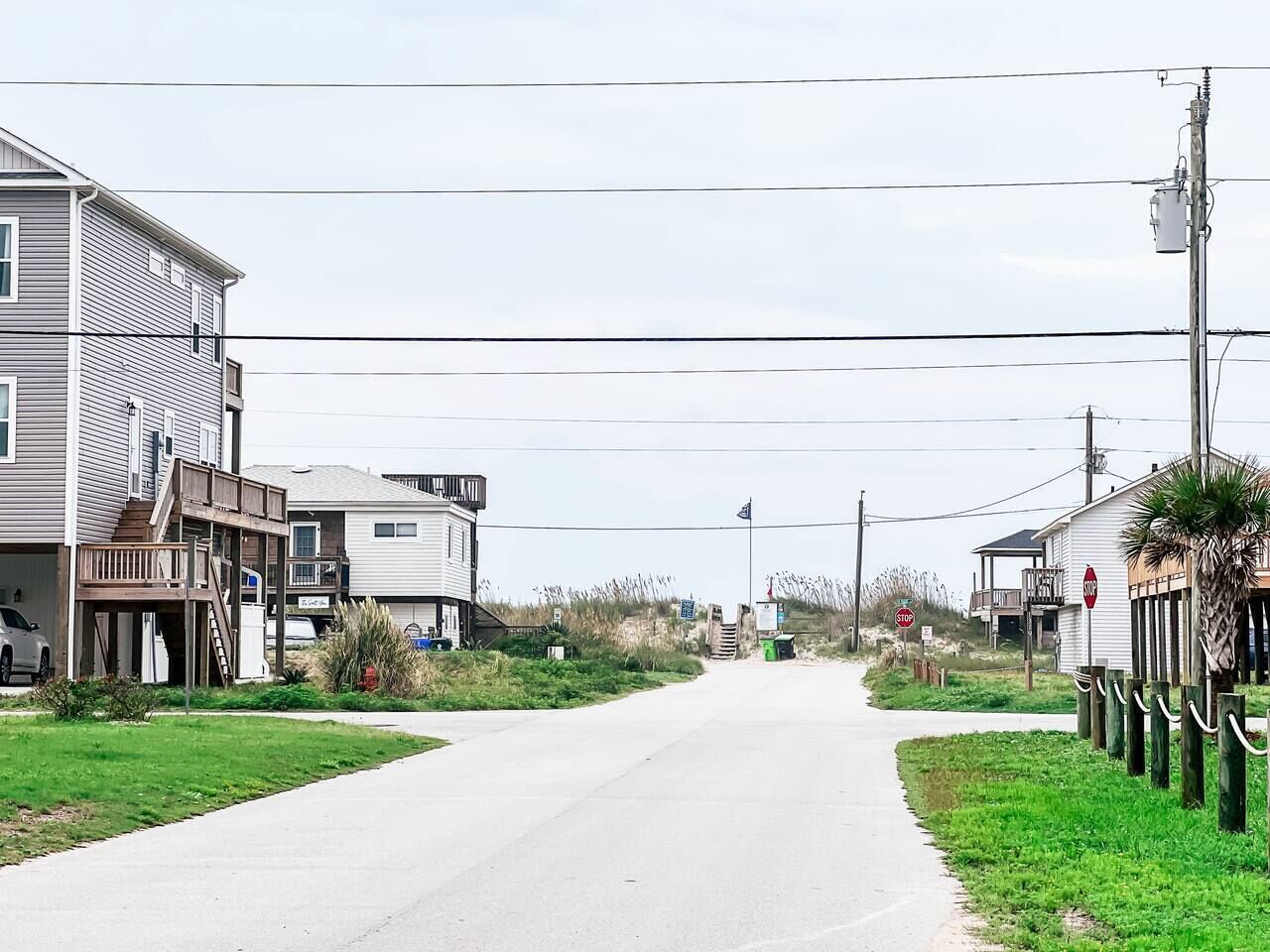 A residential street with houses on both sides, a stop sign, and utility poles.
