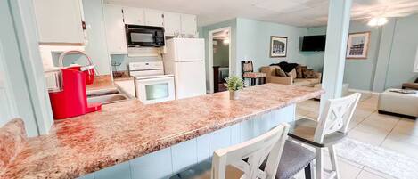 A modern kitchen with granite countertops, white cabinets, and a red coffee machine.