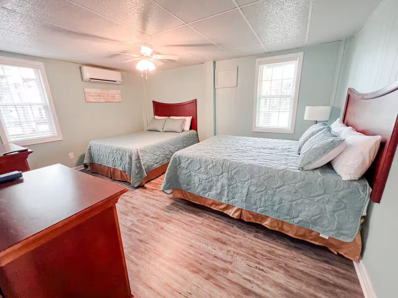 A bedroom with two beds, a desk, and a ceiling fan.