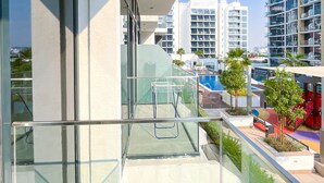 A modern building with a glass balcony, a swimming pool, and a children's play area. - Premium Riviera Studio King Bed Pool & Gym (Dubai)