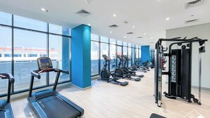 A gym with treadmills, elliptical machines, and a weight machine. - Premium Riviera Studio King Bed Pool & Gym (Dubai)